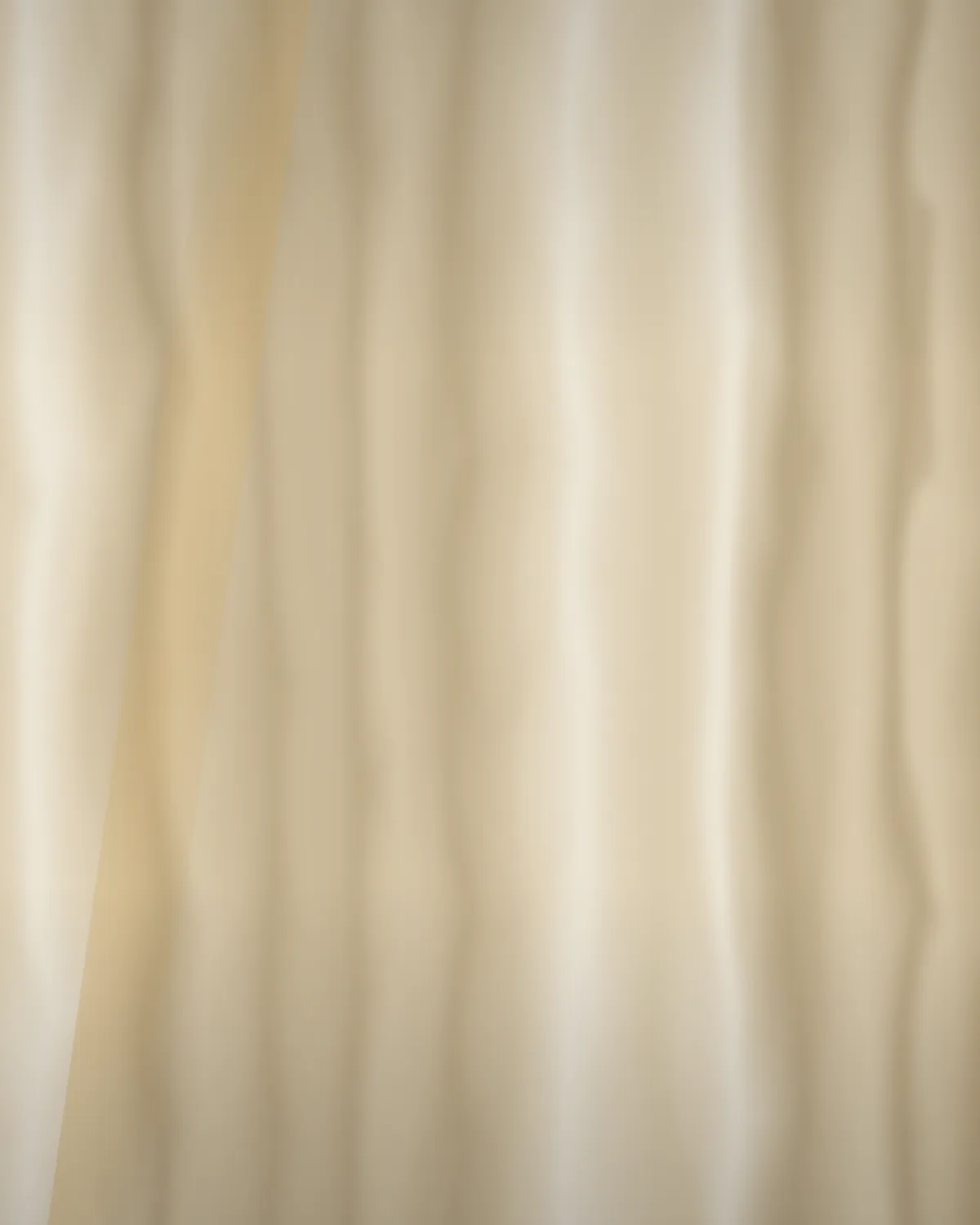 A model in a floor-length camel wool coat against porcelain seamless.